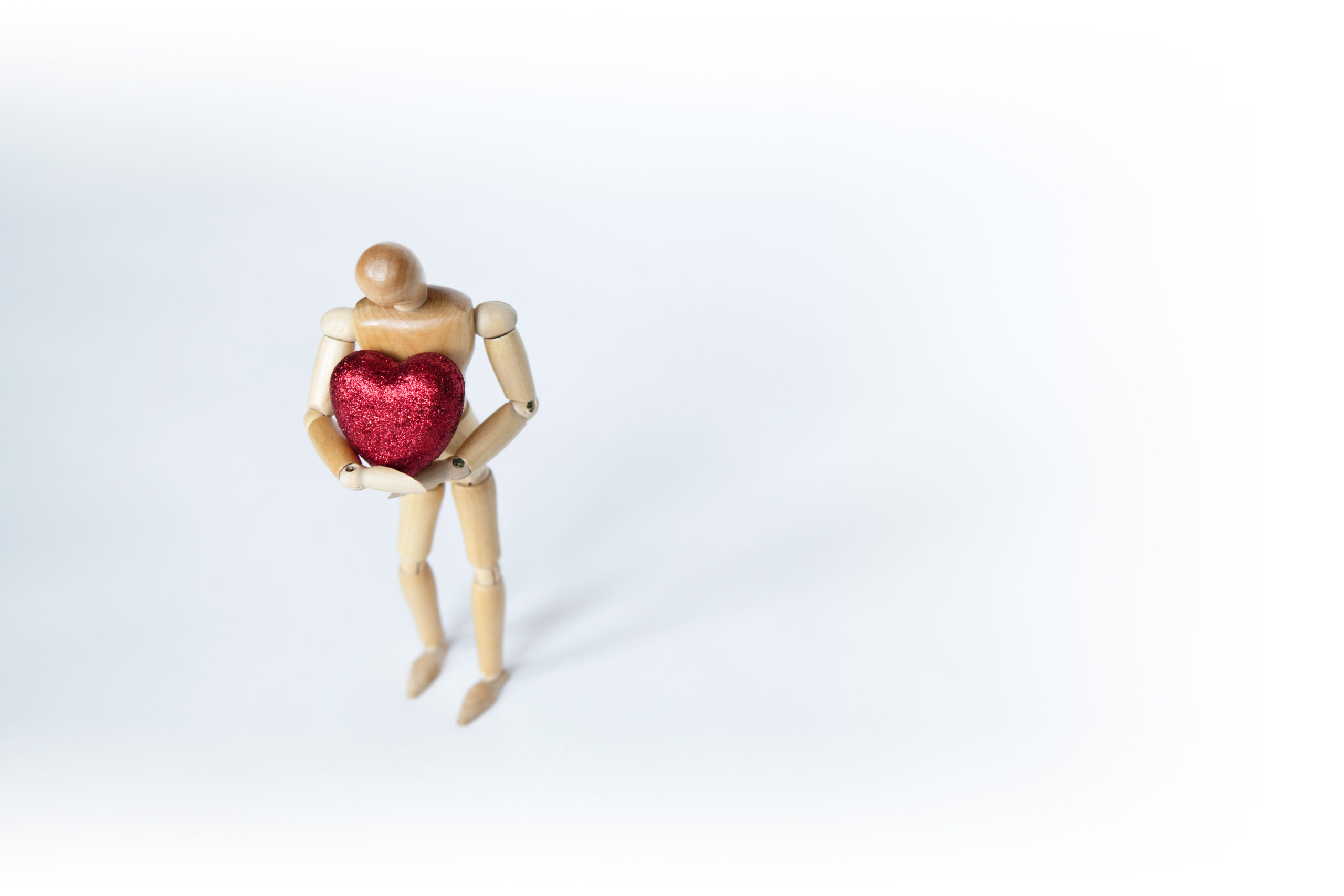 Holzfigur mit rotem Herz im Arm
